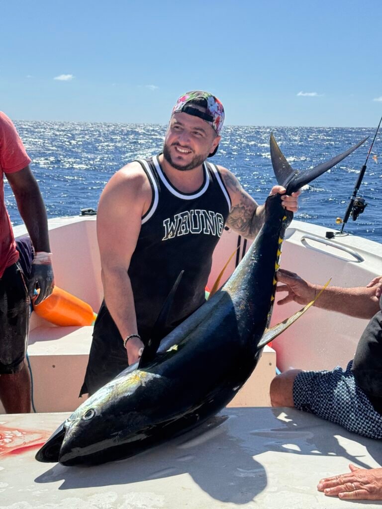 Pêcheur souriant tenant un énorme thon jaune attrapé lors d'une session de pêche au gros au large de la Martinique avec Carib Evasion.