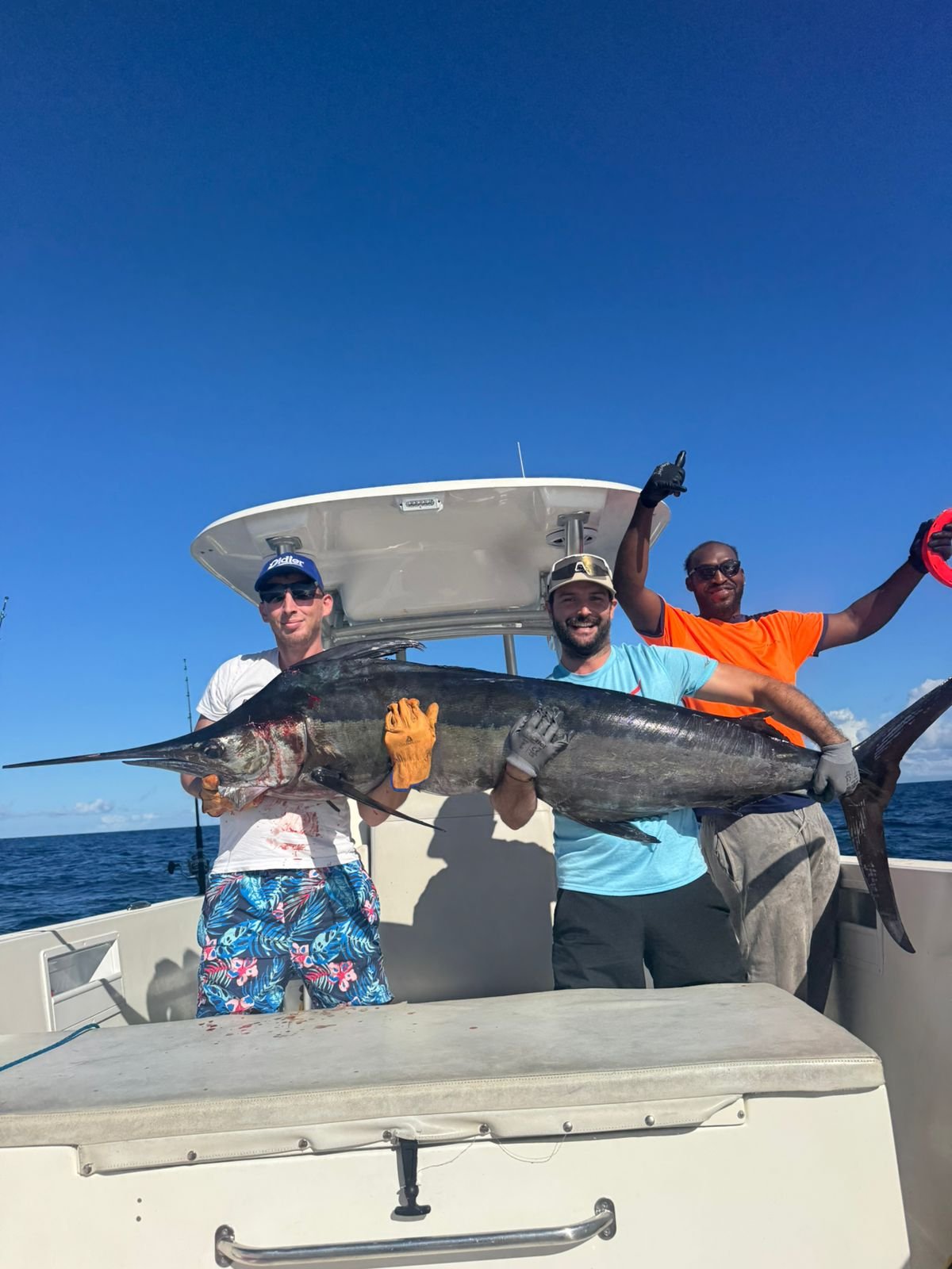 Trois pêcheurs posant fièrement avec un marlin bleu capturé au large de la Martinique